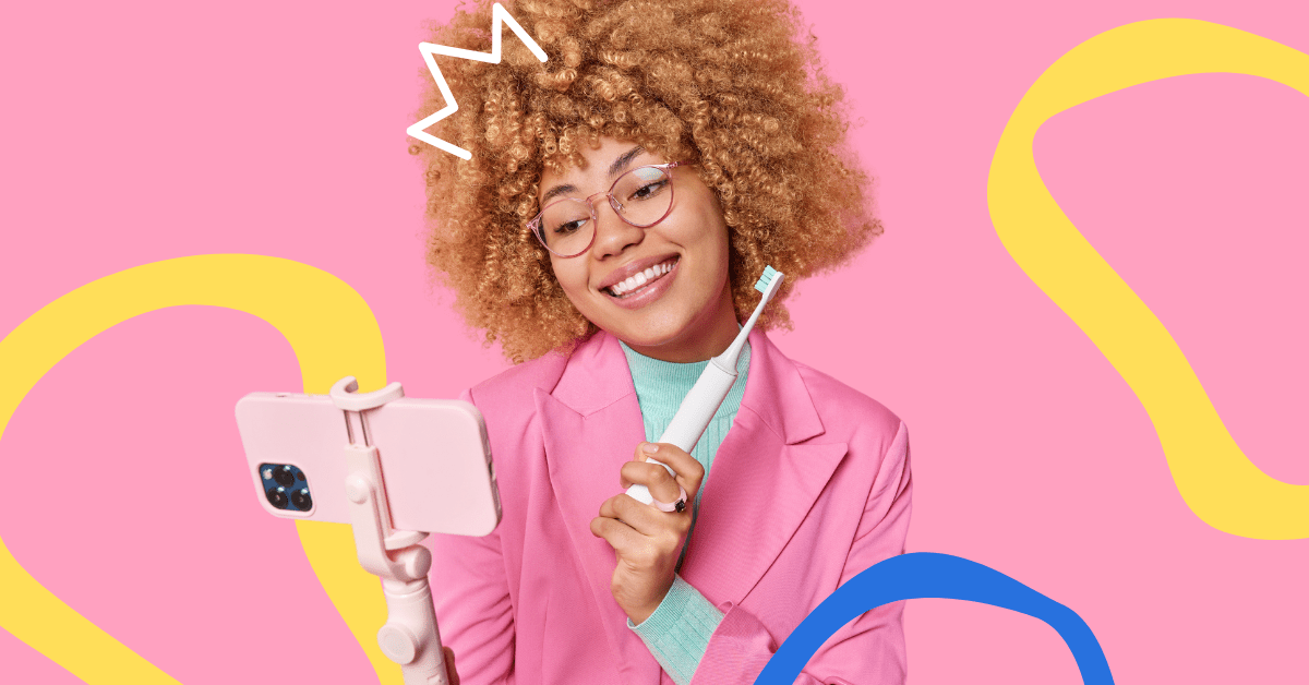 A woman wearing a pink jacket with a blonde afro creating a video with her mobile phone.